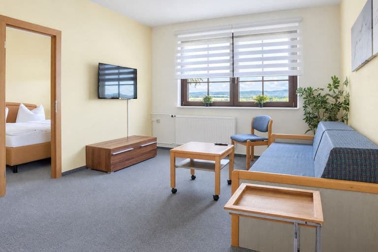 Wohnraum der Junior-Suite mit Fernseher, durch die Tür der Schlafraum