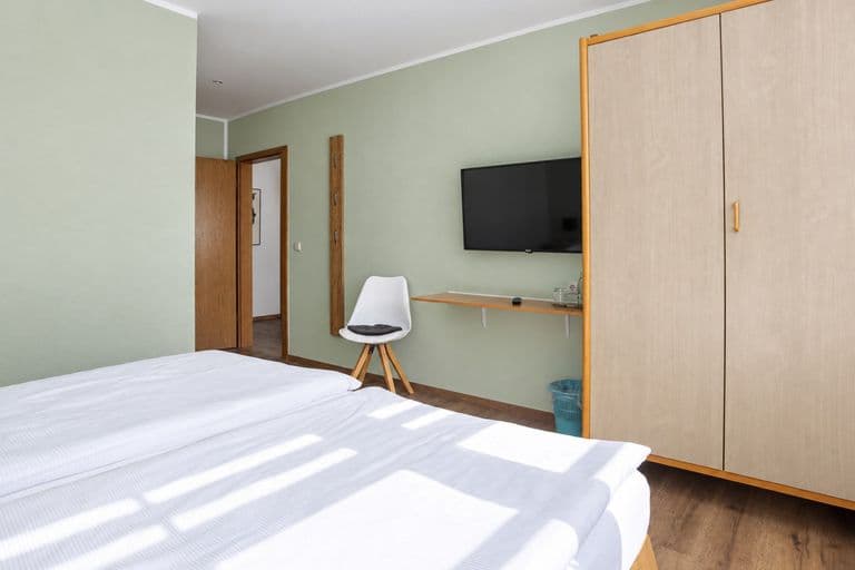 Komfortzimmer mit Kleiderschrank, Fernseher und Schreibtisch