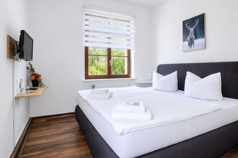 Standardzimmer mit Doppelbett, Hirschbild und Fenster ins Grüne