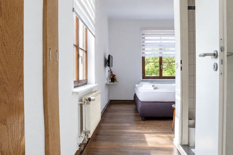 Standardzimmer: Blick vom Eingang durch den Flur zum Bett am Fenster