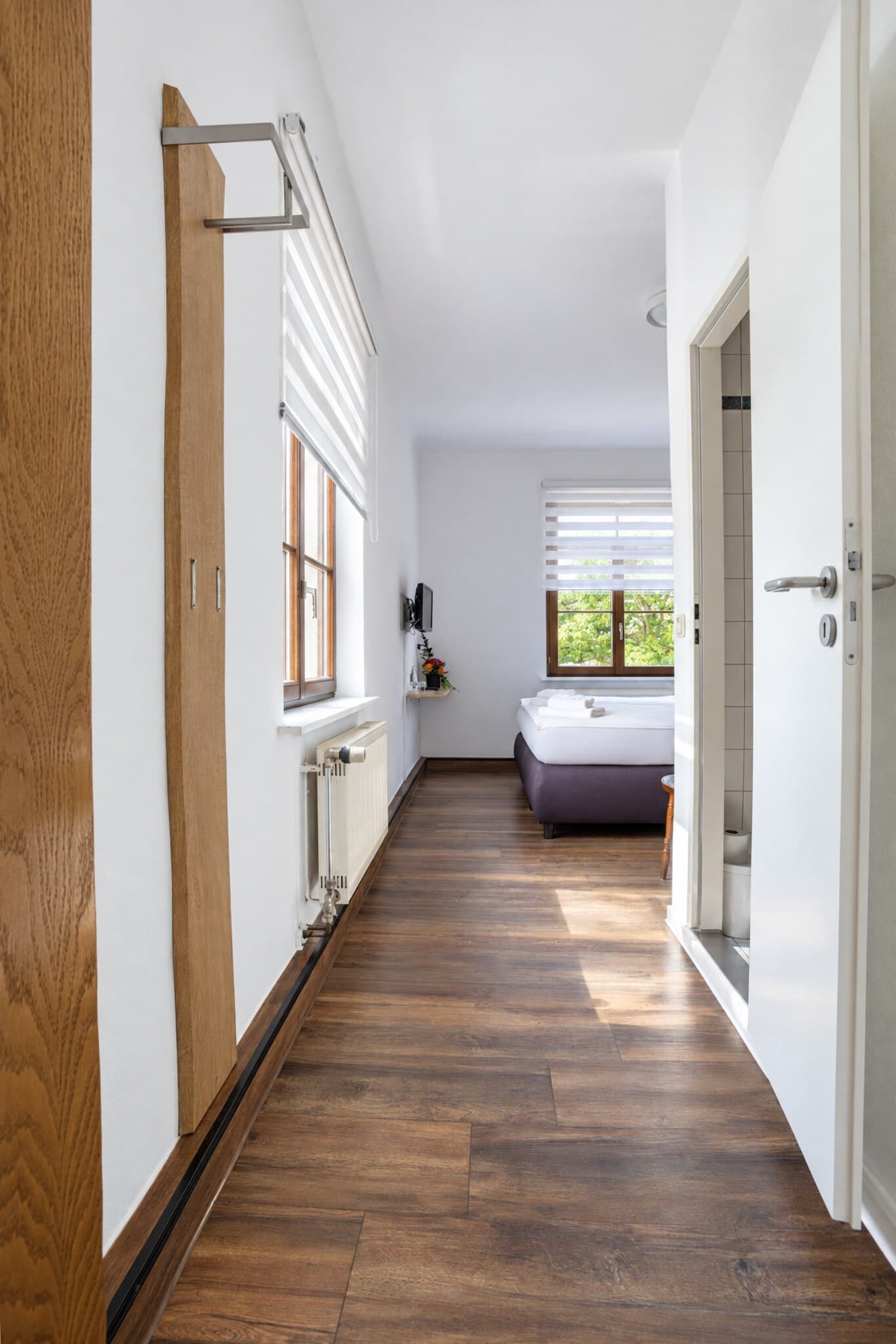 Standardzimmer: Blick vom Eingang durch den Flur zum Bett am Fenster