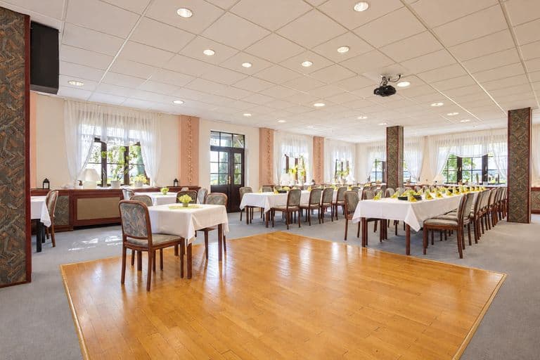 Saal mit weiß gedeckten Tafeln und hellen Fenstern