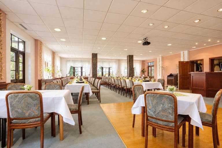 Saal mit langen Tafeln, Blick zur Theke