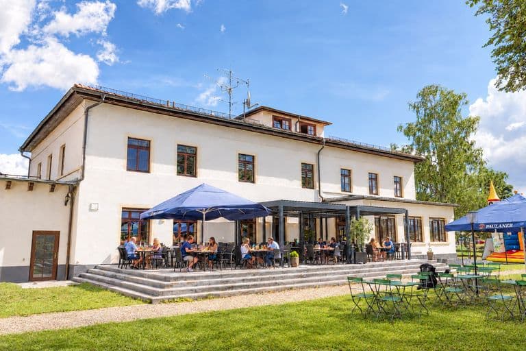 Gasthof mit Terrasse und Gästen unter Sonnenschirmen