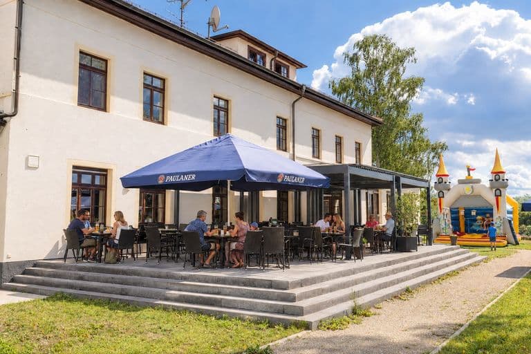 Terrasse mit Gästen, daneben die Hüpfburg für Kinder