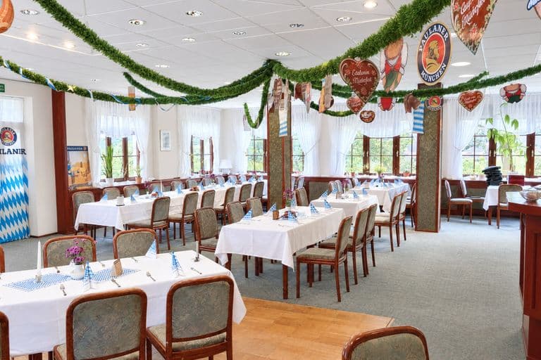 Saal mit gedeckten Tafeln und Girlanden